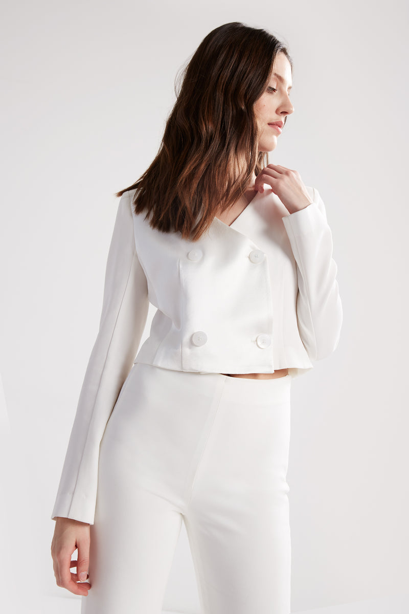 Cropped, double-breasted, collarless blazer with full length sleeves. Made in a white matte and satin fabric. 